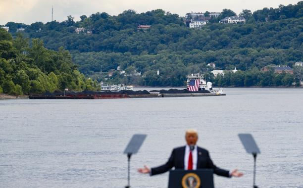 In this June 7, 2017 file photo, a coal barge is positioned as a backdrop behind President Donald Trump as he speaks during a rally at the Rivertowne Marina in Cincinnati. President Donald Trump personally promised to activate emergency legal authorities to keep dirty or economically uncompetitive coal plants from shutting down, a top American coal company said. The Trump administration now says it has no plans to do so. (John Minchillo, File/Associated Press)