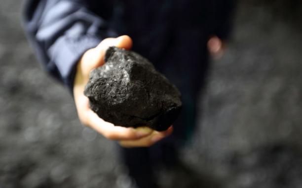 An employee holds a piece of coal in a storage yard at the Joban Joint Power Co. Nakoso coal-fired power station in Iwaki City, Fukushima Prefecture, Japan. Photographer: Tomohiro Ohsumi/Bloomberg