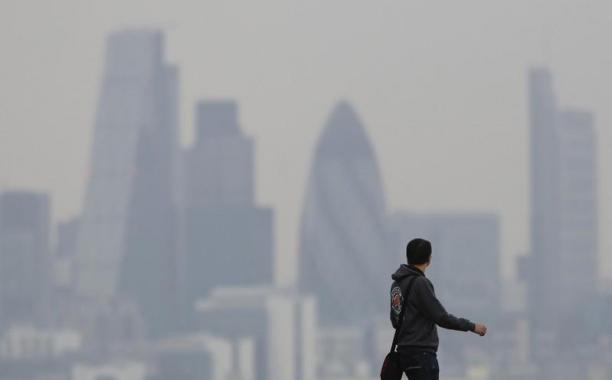 FILE PHOTO - A man walks through Greenwich Park as a haze of pollution sits over the London skyline April 3, 2014. REUTERS/Luke MacGregor